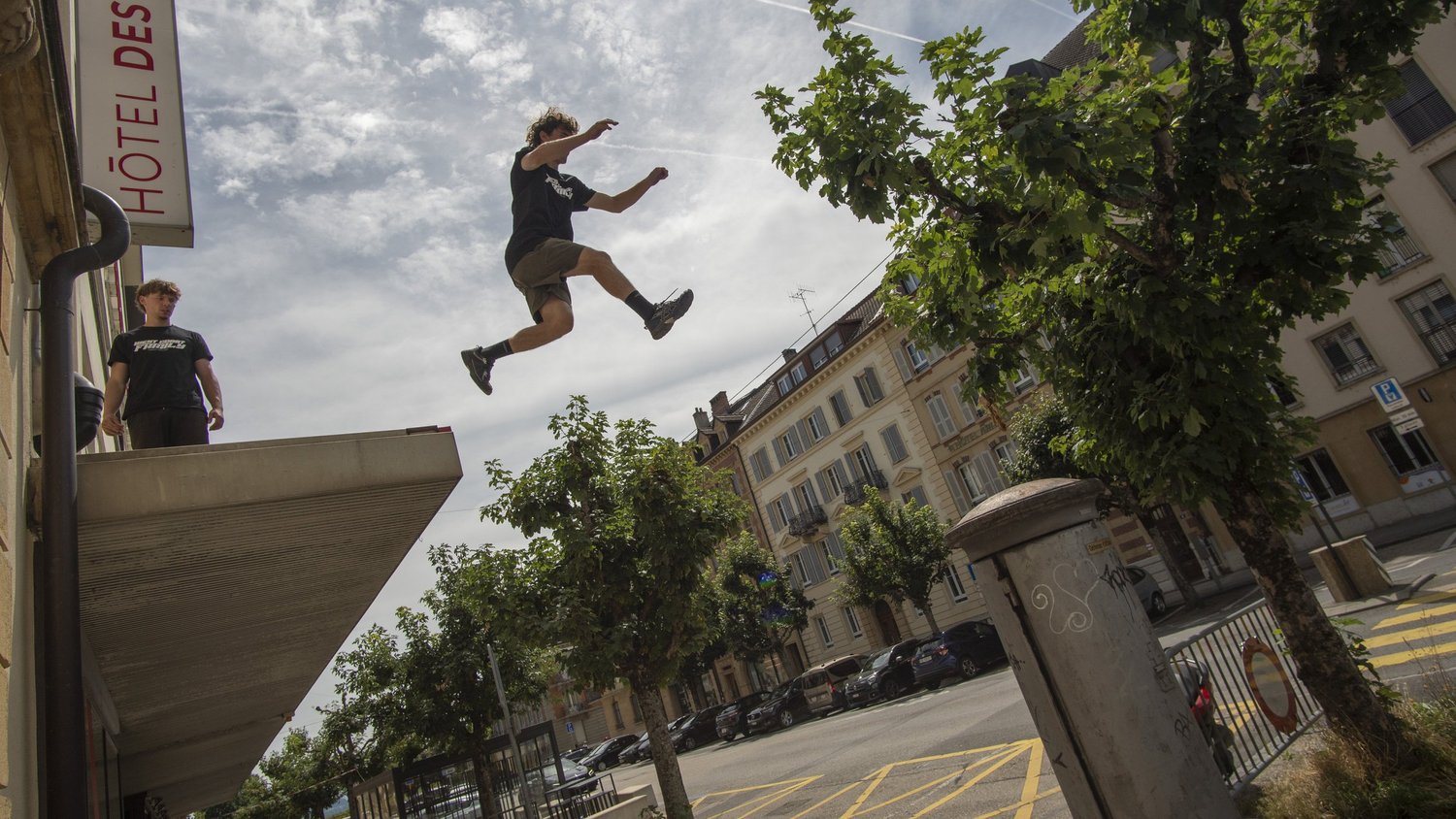 Un traceur saute entre deux murs, en pleine rue